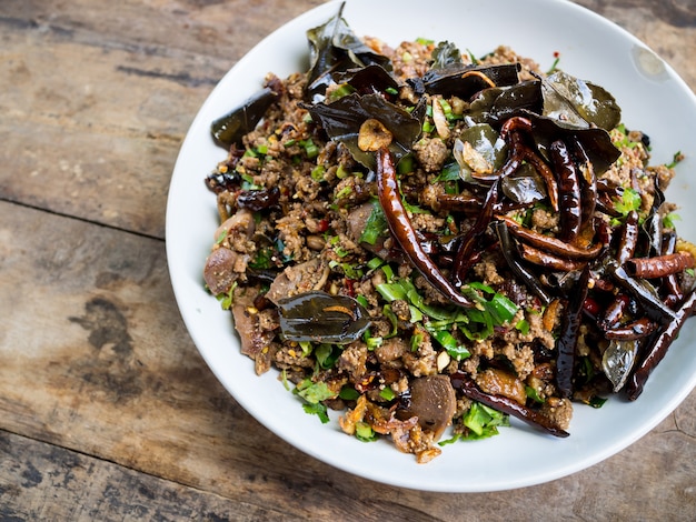 Spicy duck salad with vegetables and chillies on wood background, Thai style