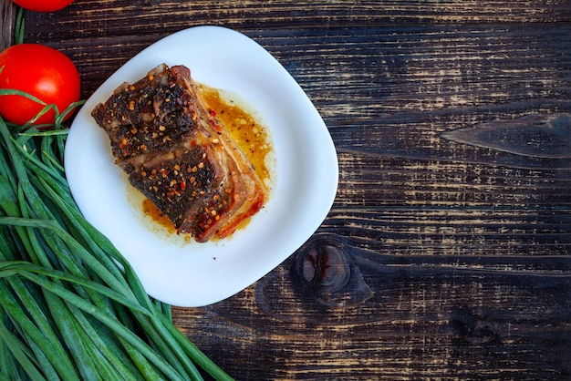 Spicy fried brisket with layers of bacon baked with herbs and paprika with fresh tomatoes and onions