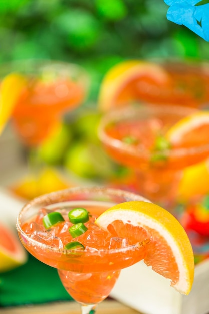 Photo spicy grapefruit margarita on ice in margarita glasses on the table in the garden.