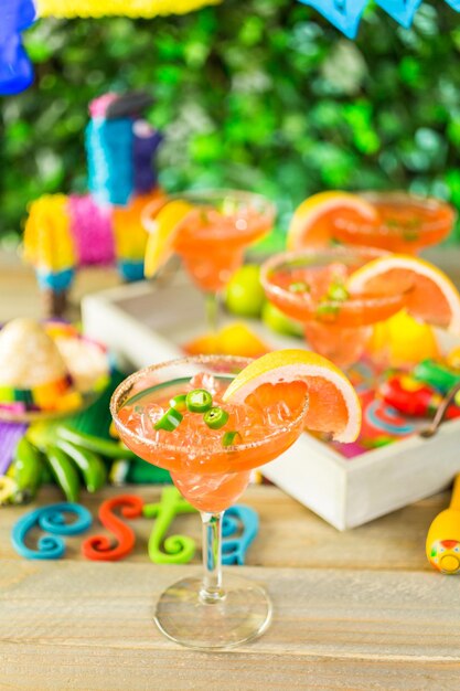 Photo spicy grapefruit margarita on ice in margarita glasses on the table in the garden.