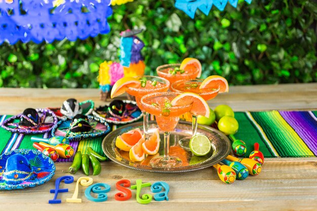 Photo spicy grapefruit margarita on ice in margarita glasses on the table in the garden.