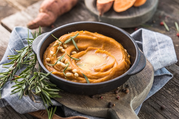 Spicy mashed sweet potato or sweet potato puree with rosemary in a saucepan on a table.  top view from above