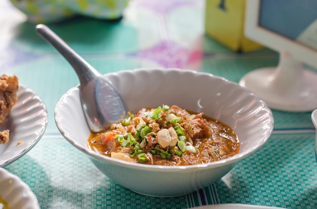 Spicy meat and tomato dip on white plate on wooden table