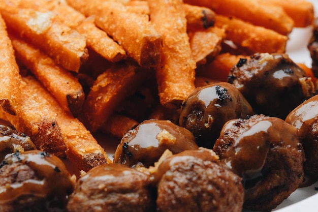 Spicy meatballs with sweet potato fries on white plate