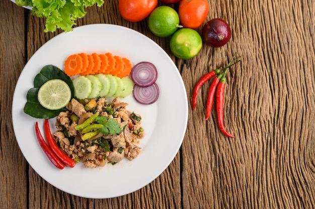 Spicy Minced Pork Salad on a white plate on wooden table Top view