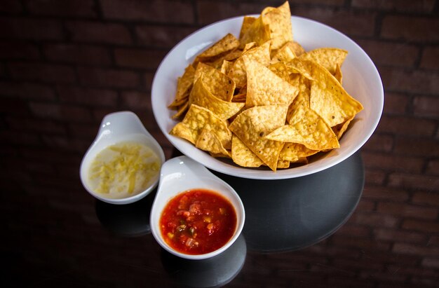 Spicy NACHOS and SALSA with dip and chilli sauce served in a dish isolated on table side view