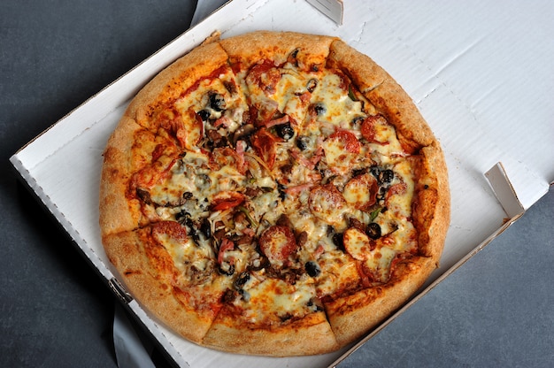 Spicy pizza with sausages in a box