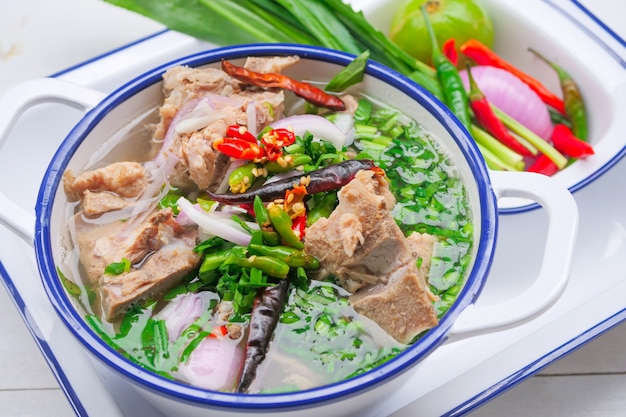 Spicy pork bone soup in Thai style Is a clear pork bone soup with large pork bones, decorated with chili and Thai herbs