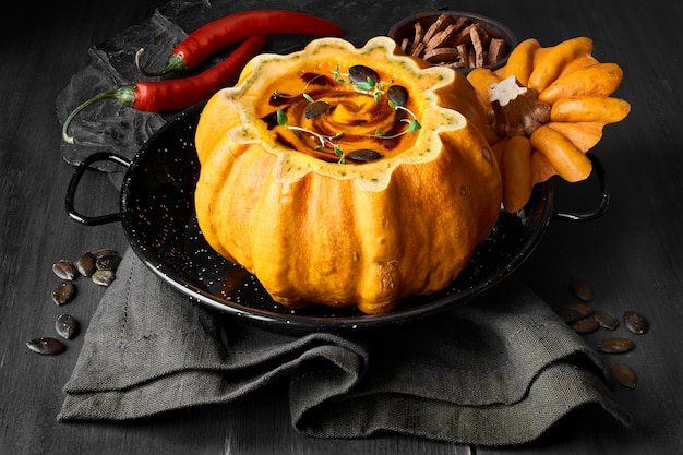 Spicy pumpkin soup served in a hollowed pumpkin on dark wood