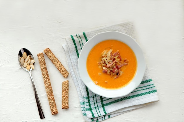 Spicy pumpkin soup with coriander in a saucepan bowl with seeds, close-up