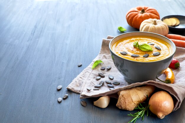 Spicy pumpkin soup with ginger, served with basil, pumpkin seeds and dried chil