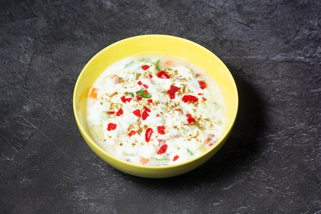 매운 라이타 야채 오이 민트와 토마토는 인도와 방글라데시 음식의 회색 배경 평면도에서 분리된 접시에 제공됩니다.