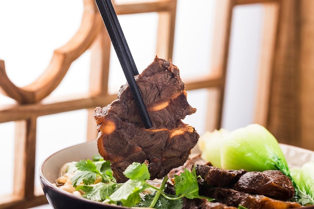 Spicy red soup beef noodle in a bowl on wooden table