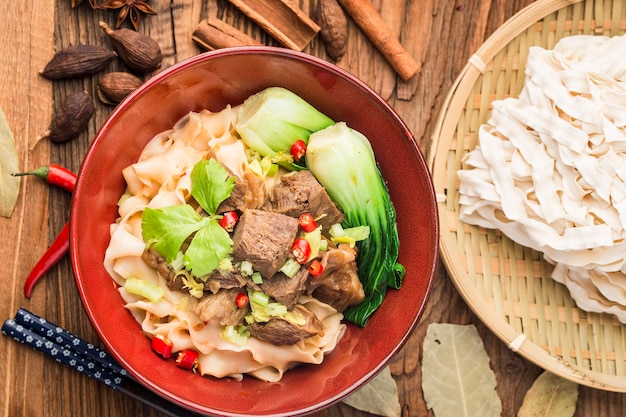 Spicy red soup beef noodle in a bowl on wooden table