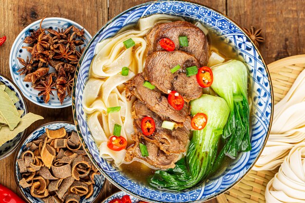 Photo spicy red soup beef noodle in a bowl on wooden table