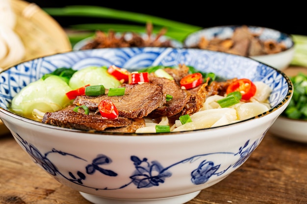 木製のテーブルのボウルにスパイシーな赤いスープ牛肉麺