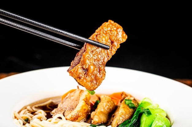 木製のテーブルのボウルにスパイシーな赤いスープ牛肉麺