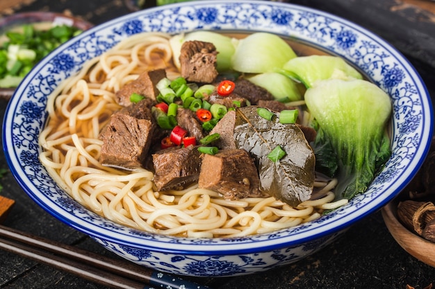 木製のテーブルのボウルにスパイシーな赤いスープ牛肉麺