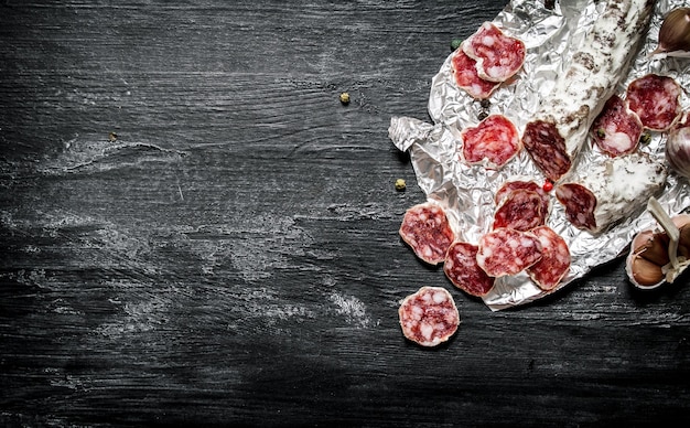 Spicy salami with spices on the foil