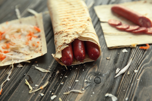 Spicy sausages in pita bread on a wooden table.