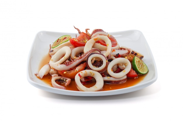 Photo spicy seafood salad with squid on white wall.