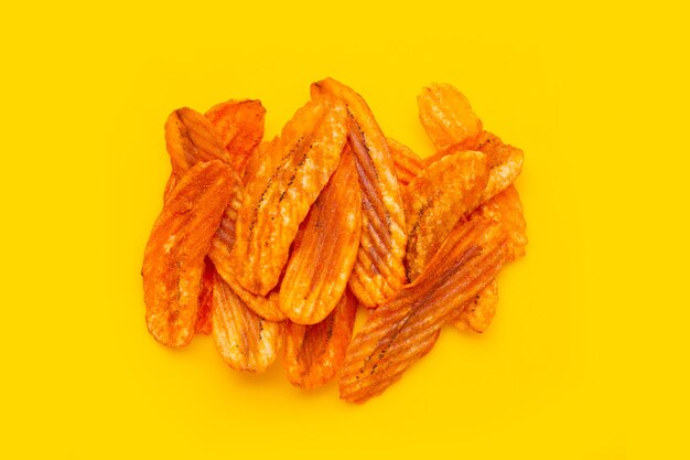 Spicy snack, Banana slice chips paprika flavor on yellow background.