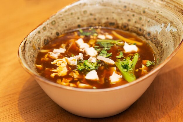 Spicy and sour soup with chicken and broccoli on a table asian cuisine