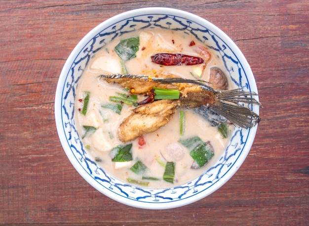 Spicy and sour Soup with Fried Fish on the wooden table, Thai food