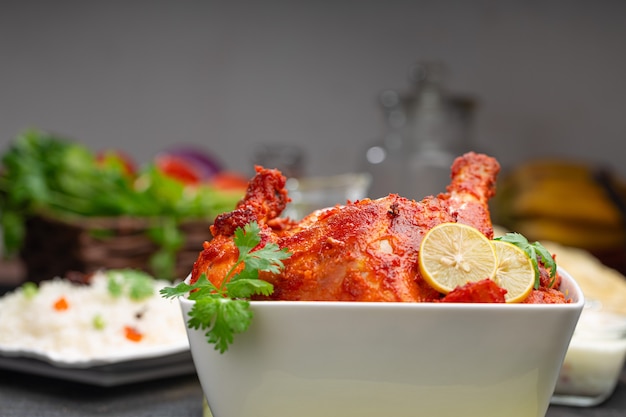 Spicy Tandoori chicken garnished with coriander leaf in square shaped white bowl