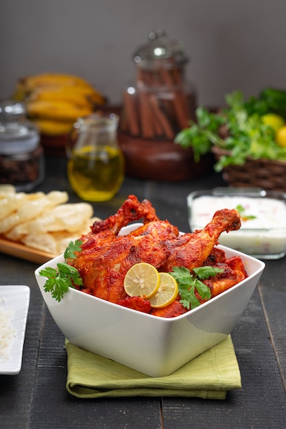 Spicy Tandoori chicken garnished with coriander leaf in square shaped white bowl