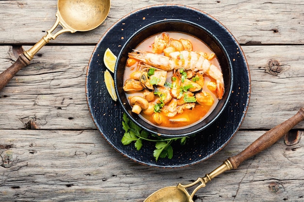 Photo spicy thai soup tom yam in plate on rustic wooden background