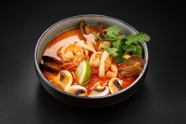 Острый тайский суп Tom Yam с кокосовым молоком, тигровыми креветками, мидиями, кальмарами, форелью и грибами. рис и лайм