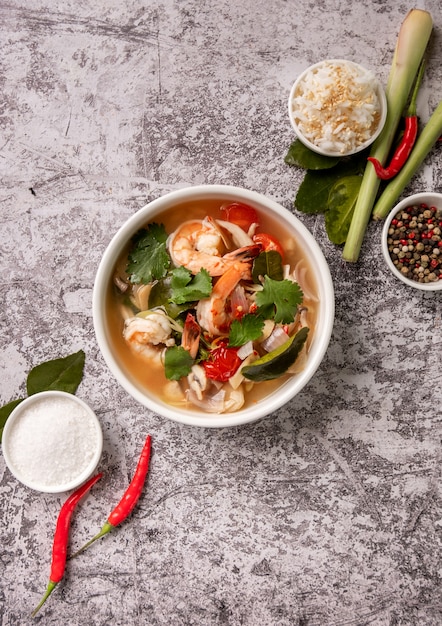 Photo spicy tom yam kung, tom yum sour soup with shrimp, prawn, coconut milk, lemongrass and chili pepper in a bowl