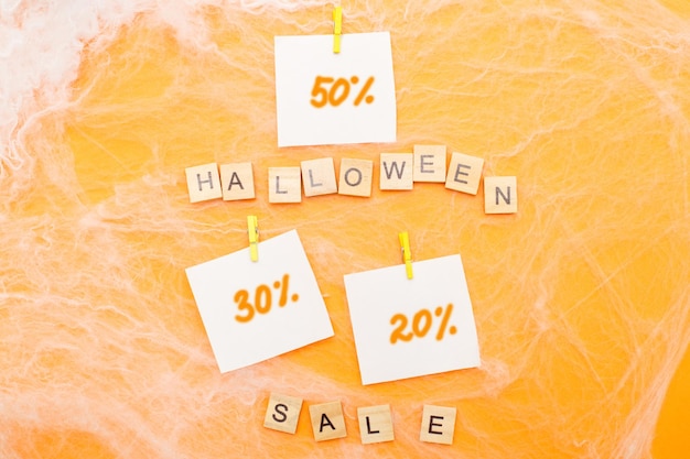 Spider web and the inscription halloween sale on orange background with discount paper stickers