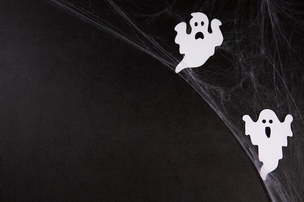 Spider web with white ghosts on black background