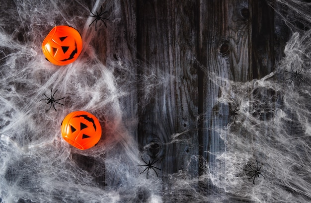 Spider web on wooden background with toy halloween pumpkins. Copy space. Selective focus.