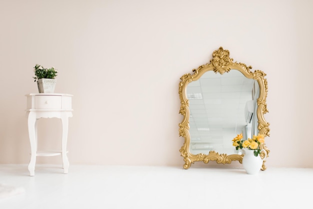 Spiegel in een klassieke gouden lijst en ingemaakte bloemen in het interieur van de woonkamer