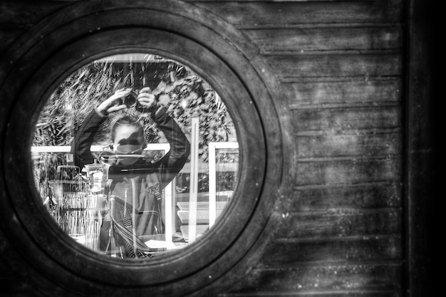 Foto spiegelbeeld van een fotograafende vrouw op het glazen raam van een gebouw autoportret