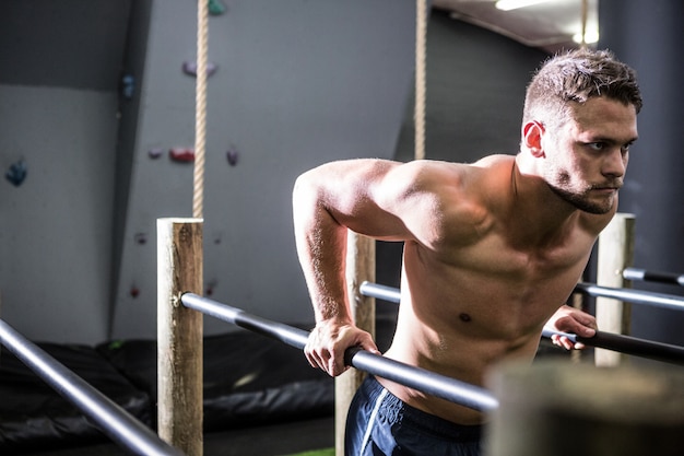 Spiermens die op parallelle staven in crossfitgymnastiek uitoefenen