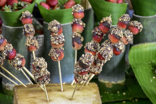 Spiesjes met verse aardbeien zijn versierd met chocolade, munt en amandelen