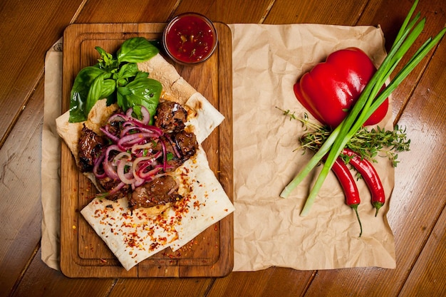 Spiesjes van lamsvlees met saus, met uien, lavash. Turks en Arabisch - Oosterse traditionele kebab met groenten, uien, tomaten, paprika, pitabroodje en sla op een houten achtergrond.