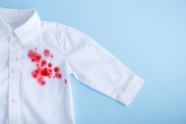 Spill beverage on clothes Bright pink stain on a white shirt from the front isolated on blue backg