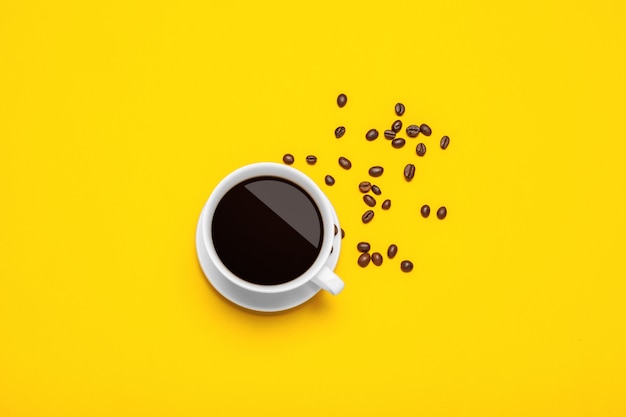 Spilled coffee beans on a bright yellow