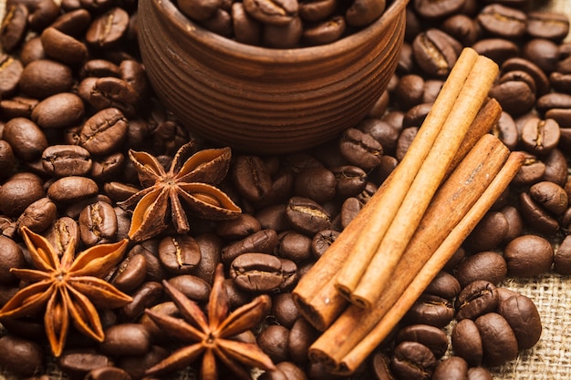 Spilled coffee beans in clay handmade cup with cinnamon and anise