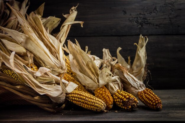 Photo spilled corn in a basket on dark rustic background