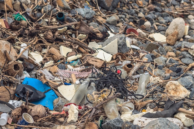 Spilled garbage on sea shore stones gray gravel empty used\
dirty waste plastic bottles environmental total pollution\
ecological problem abstract composition textured nature background\
web design