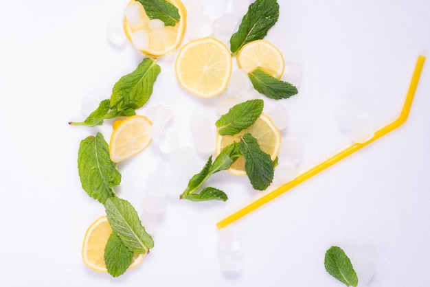 Spilled glass of refreshing summer cocktail with ice, lemon and mint on white background.