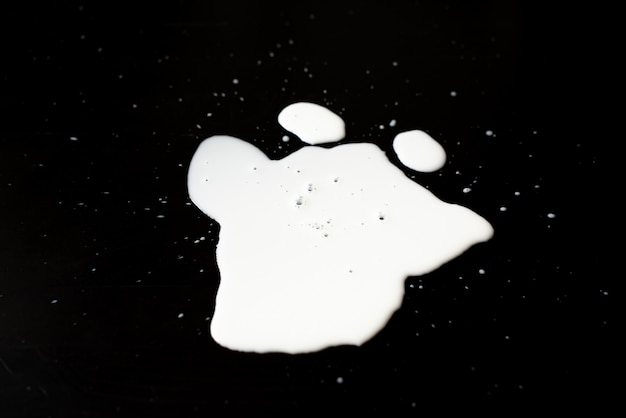 Photo spilled milk puddle isolated on black background and texture with clipping path, top view