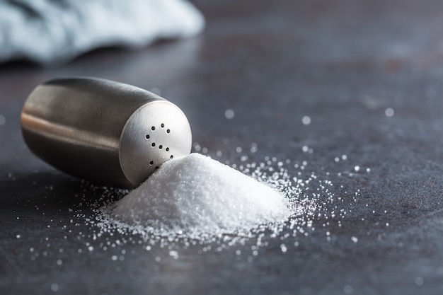 Spilled salt with staniless salt shaker - Closeup.