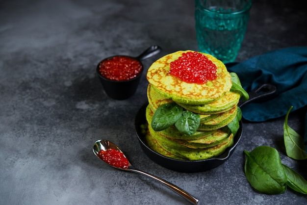 Spinach American pancake stacked in a small pan on a dark background. Horizontal photo with copy space